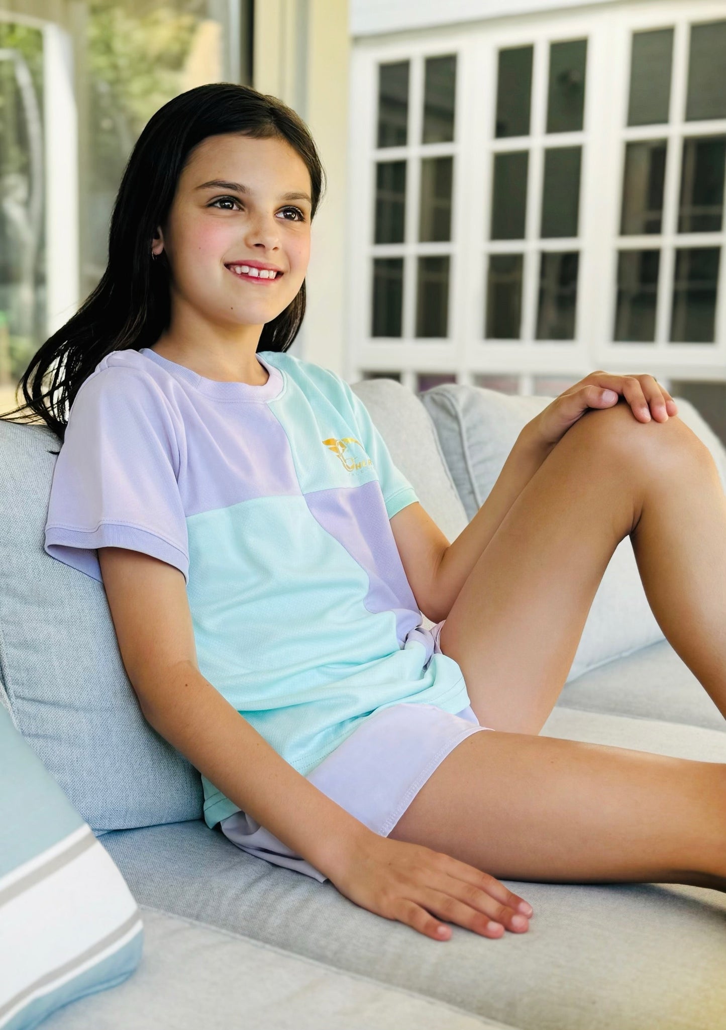 Colorful Betty Soccer Shirt with pastel green, pink, yellow, and purple block design, curved hem, and gold leaf logo.