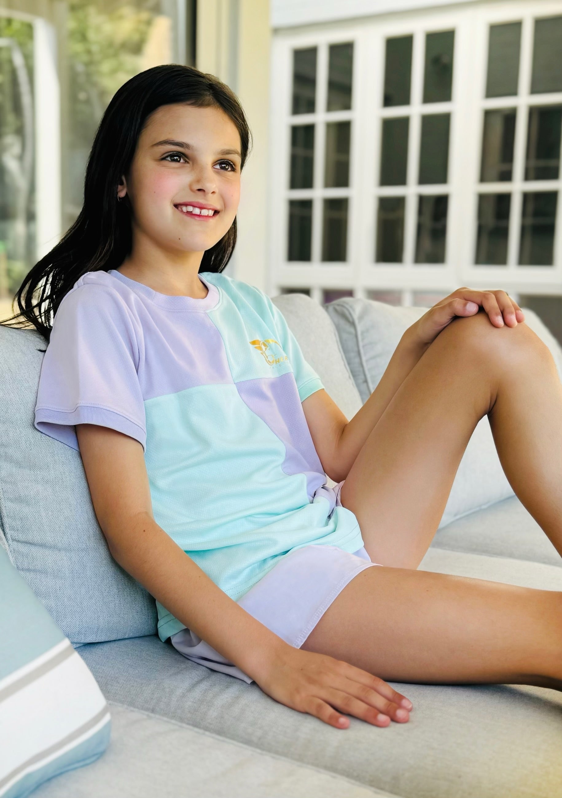 Colorful Betty Soccer Shirt with pastel green, pink, yellow, and purple block design, curved hem, and gold leaf logo.