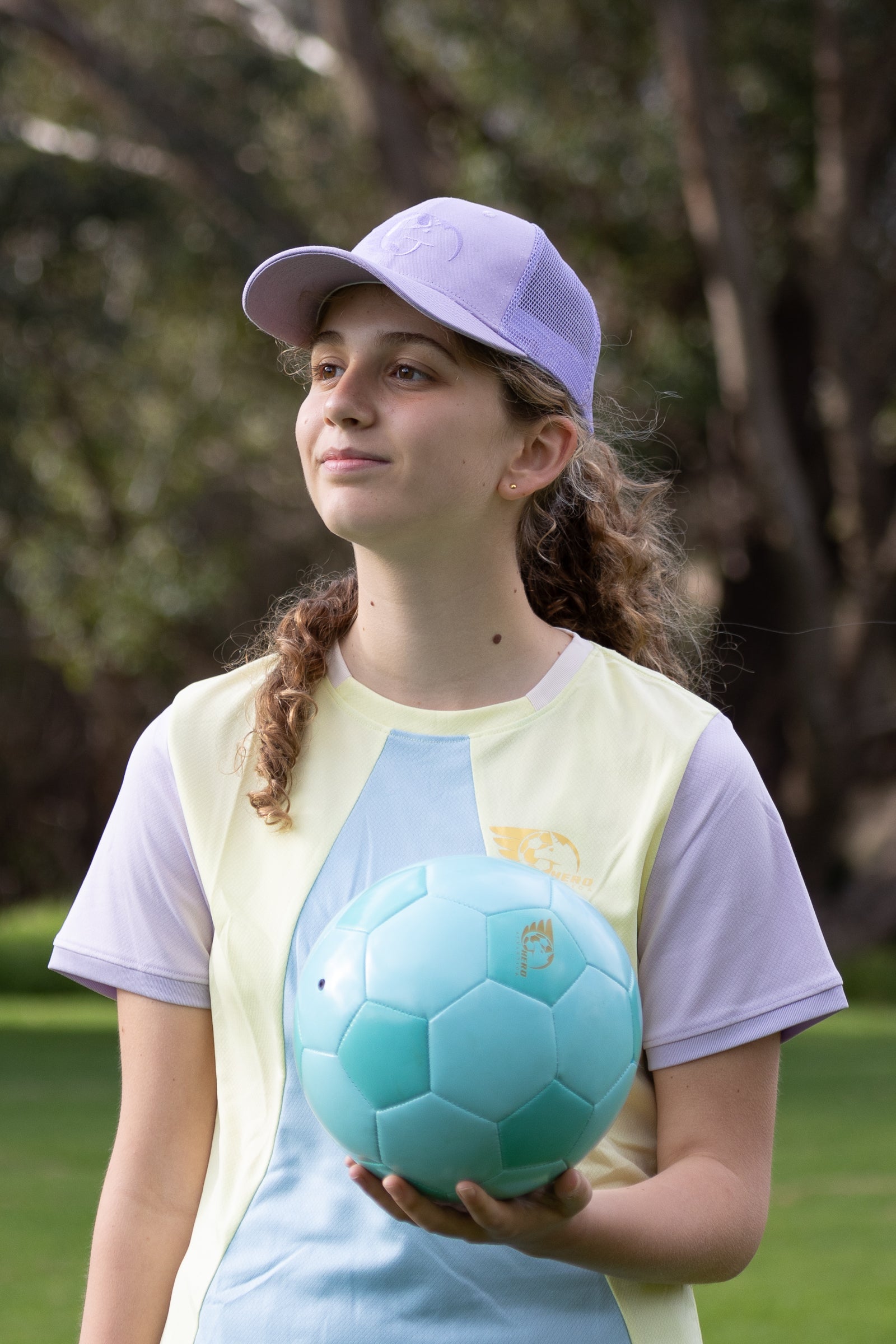 Purple Trucker Cap with embroidered logo, cotton-rich construction, mesh back, and snapback design on a person outdoors.