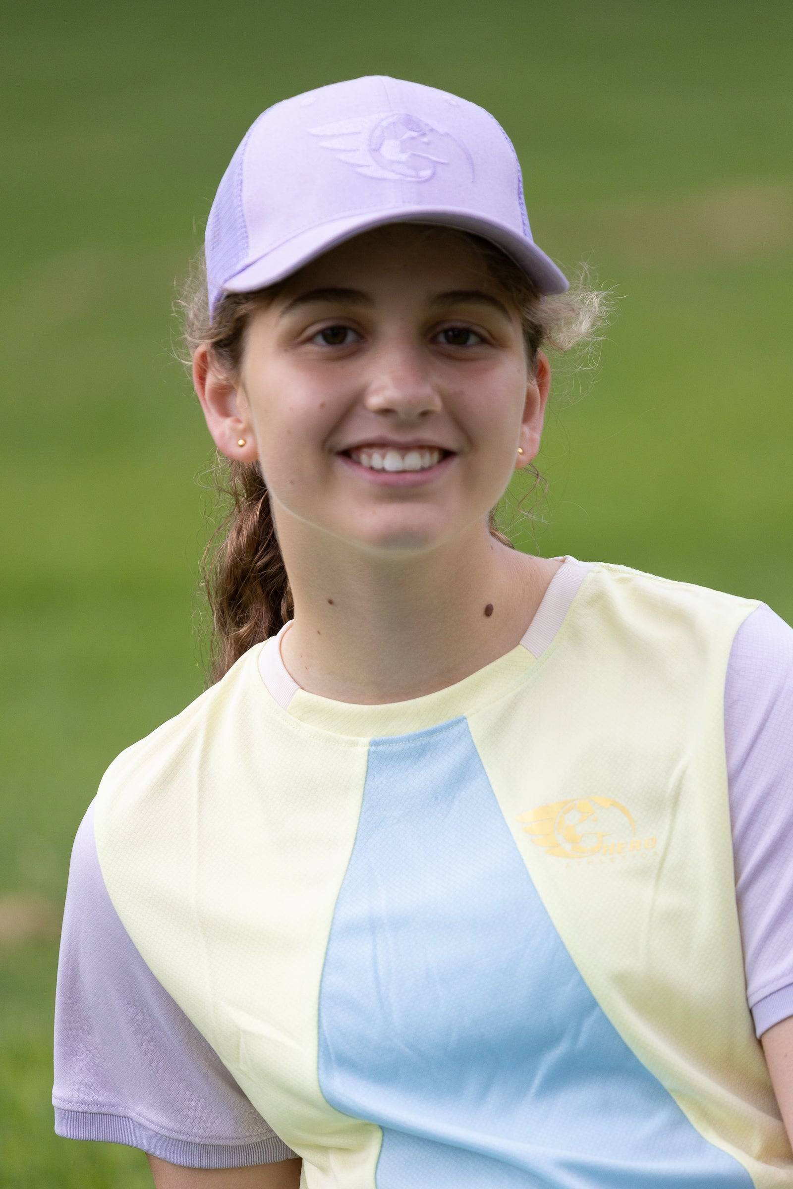 Purple trucker cap with monochrome embroidery and mesh back, worn by person outdoors.
