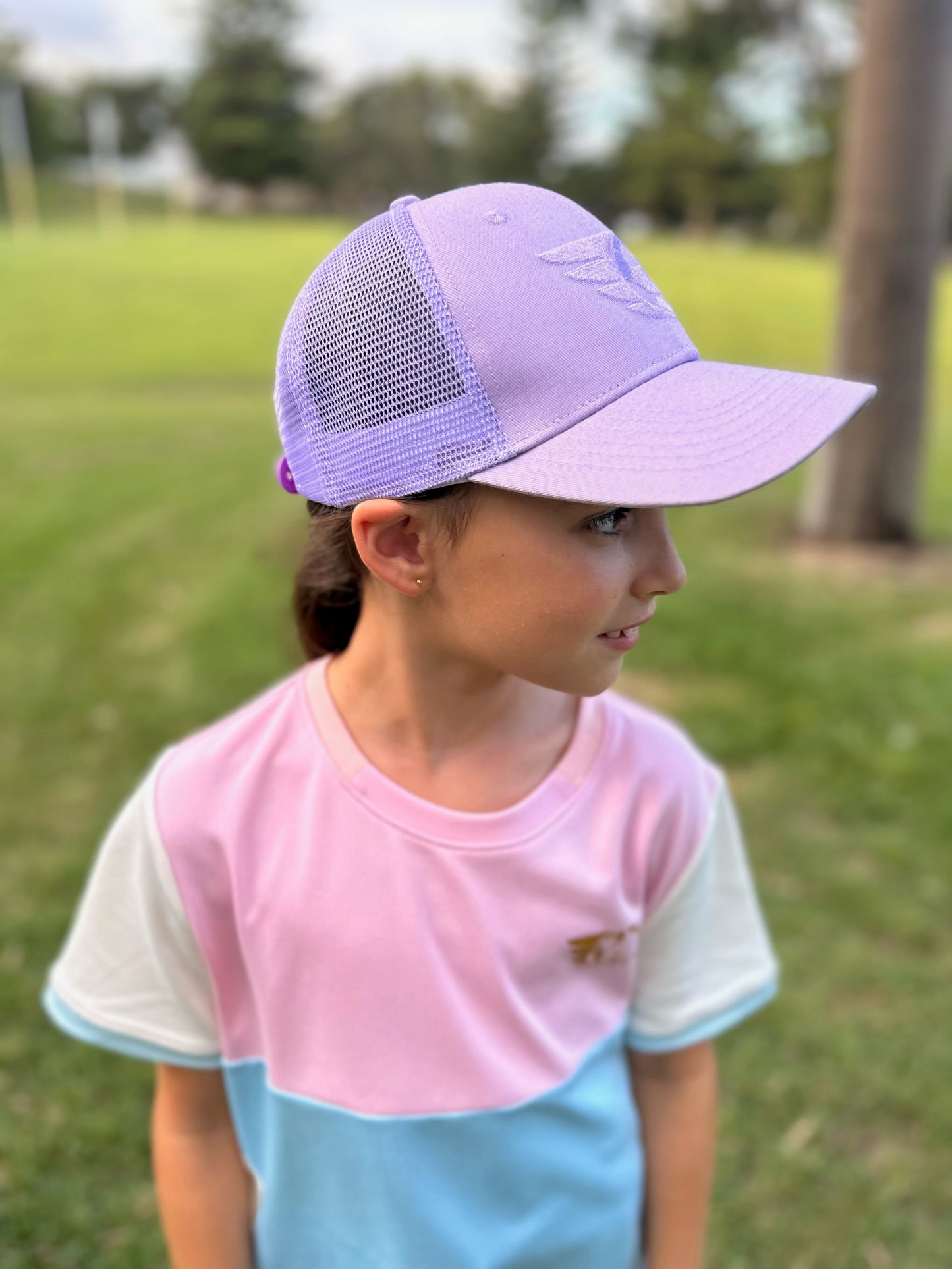 Purple Trucker Cap with mesh back and embroidered logo worn by a child outdoors.