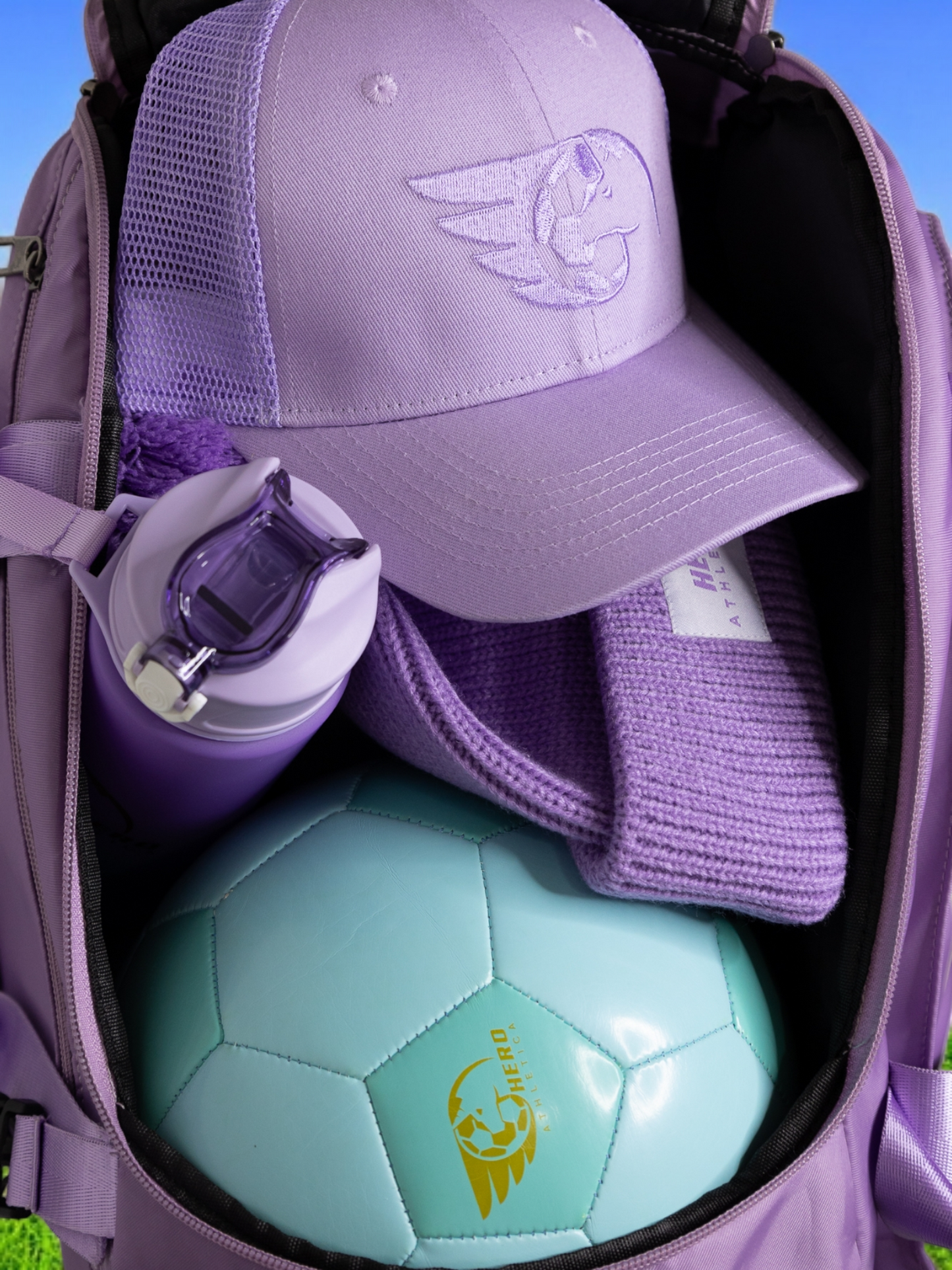 Purple trucker cap with embroidered logo in a backpack, featuring cotton-rich fabric and mesh back for breathability.